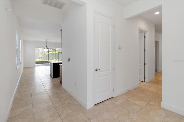 hallway featuring light tile patterned floors, baseboards, and visible vents