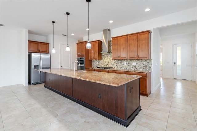 kitchen with brown cabinets, light stone countertops, stainless steel appliances, wall chimney range hood, and backsplash