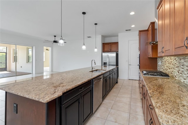 kitchen featuring tasteful backsplash, a spacious island, appliances with stainless steel finishes, brown cabinets, and a sink