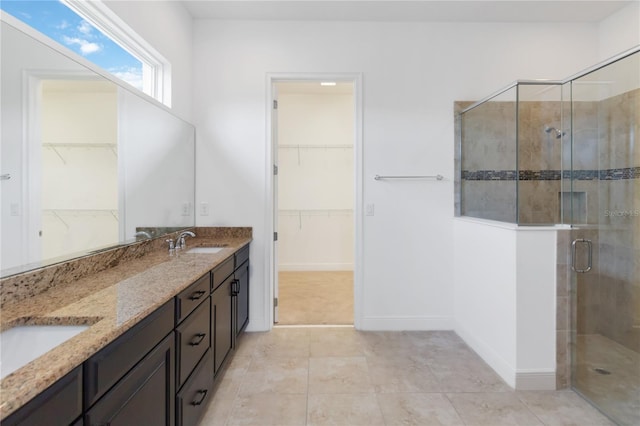 bathroom with a stall shower, a sink, baseboards, and double vanity