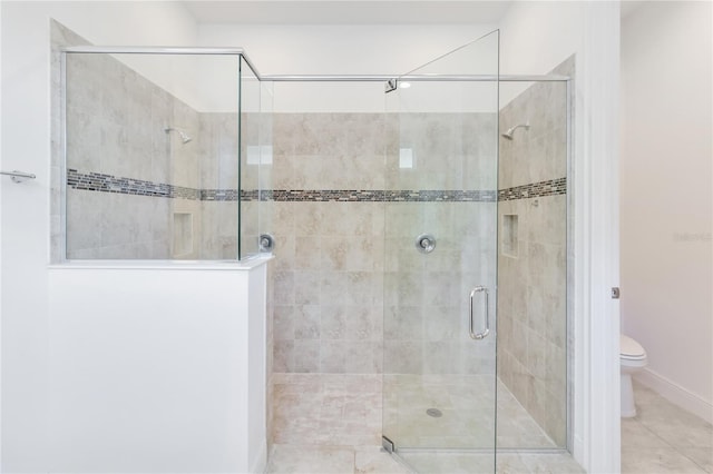 bathroom with a shower stall, toilet, and tile patterned floors