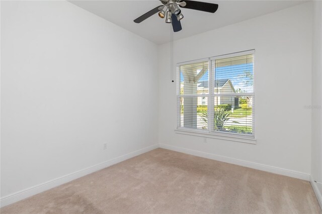 unfurnished room featuring a ceiling fan, light carpet, and baseboards