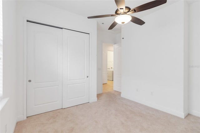 unfurnished bedroom with light carpet, baseboards, a ceiling fan, washer / clothes dryer, and a closet