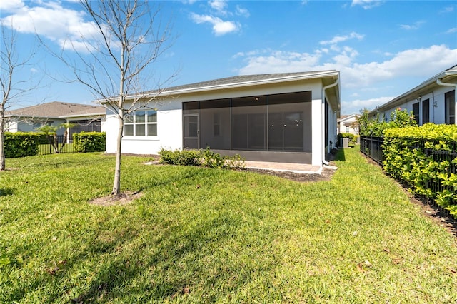 rear view of house featuring a sunroom, a fenced backyard, stucco siding, and a yard