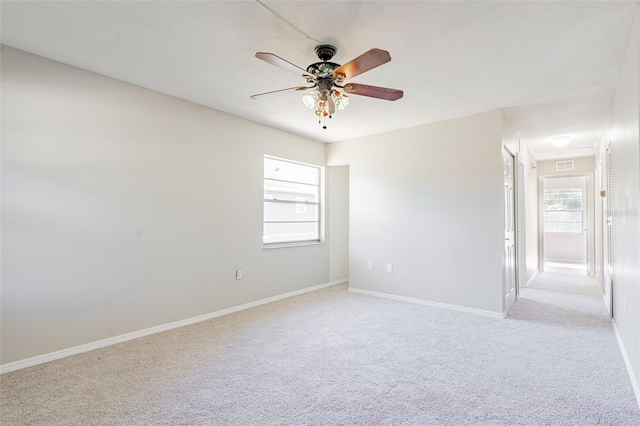 unfurnished room featuring visible vents, carpet, a ceiling fan, and baseboards