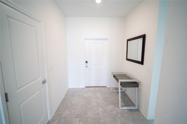 hallway with light tile patterned flooring and baseboards