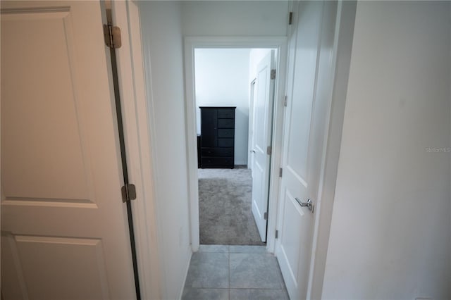 corridor with light colored carpet and light tile patterned floors