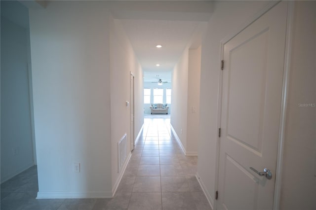 corridor featuring light tile patterned floors, recessed lighting, visible vents, and baseboards