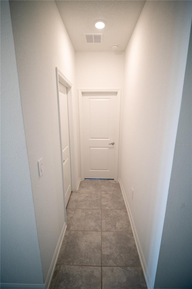 hallway featuring tile patterned flooring, visible vents, and baseboards