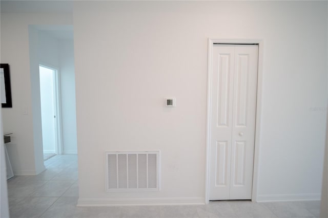 hall featuring light tile patterned floors, baseboards, and visible vents