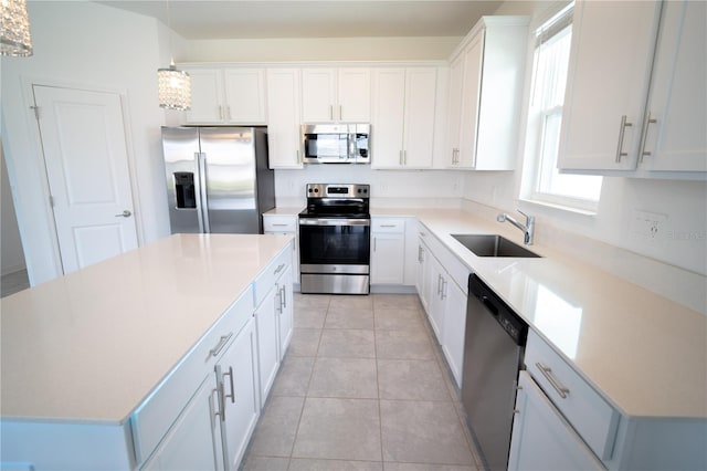 kitchen with light tile patterned floors, a sink, white cabinetry, appliances with stainless steel finishes, and a center island