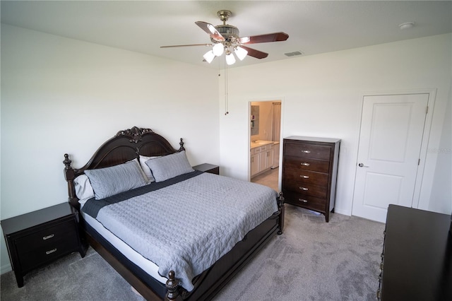 bedroom featuring light colored carpet, visible vents, ceiling fan, and ensuite bath