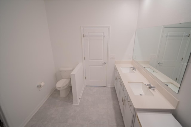 bathroom featuring double vanity, a sink, toilet, and baseboards