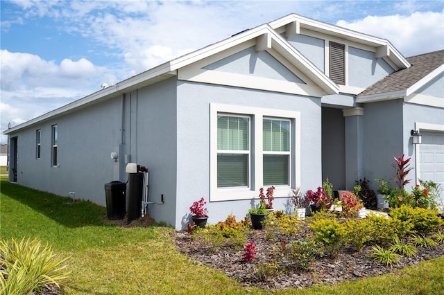 view of property exterior with an attached garage, stucco siding, and a yard