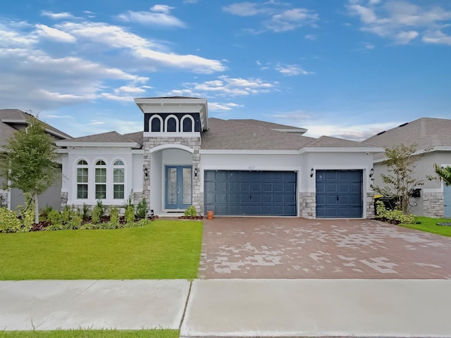 view of front of house with a garage, stone siding, a front lawn, and decorative driveway