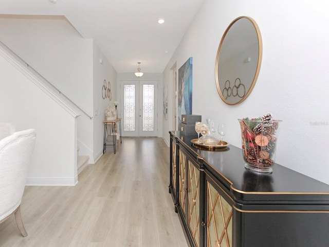 entryway with stairs, french doors, light wood finished floors, and baseboards