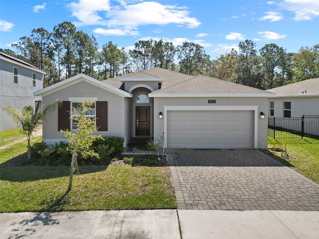 ranch-style home with a garage, fence, decorative driveway, a front yard, and stucco siding