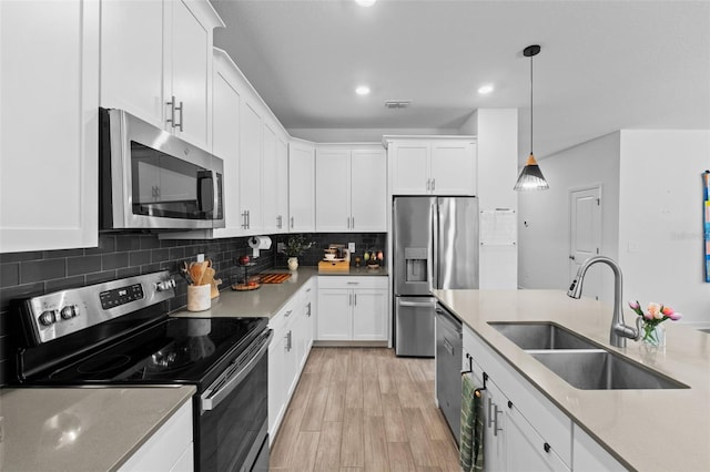 kitchen featuring stainless steel appliances, visible vents, backsplash, white cabinets, and a sink