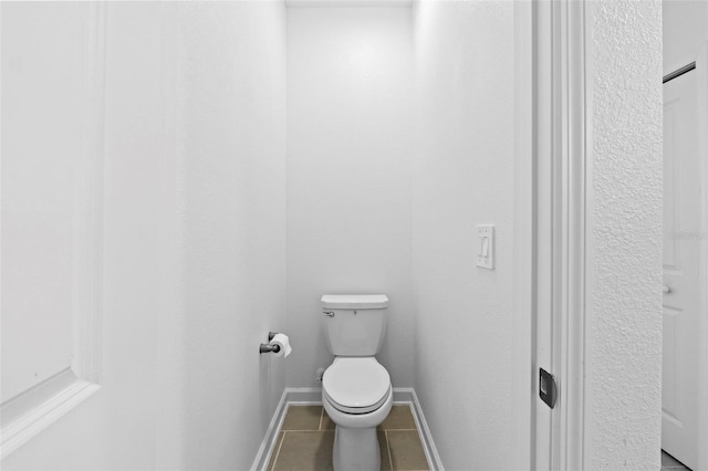 bathroom featuring toilet, baseboards, and tile patterned floors