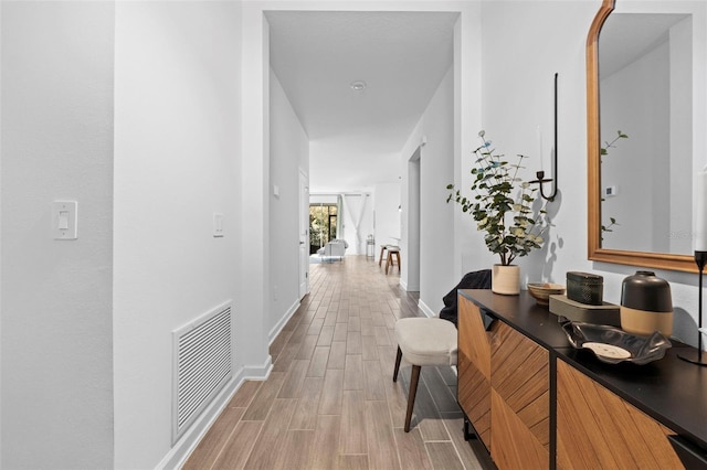 corridor with wood tiled floor, visible vents, and baseboards