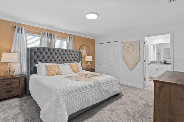 bedroom with crown molding, baseboards, light carpet, a closet, and ensuite bath