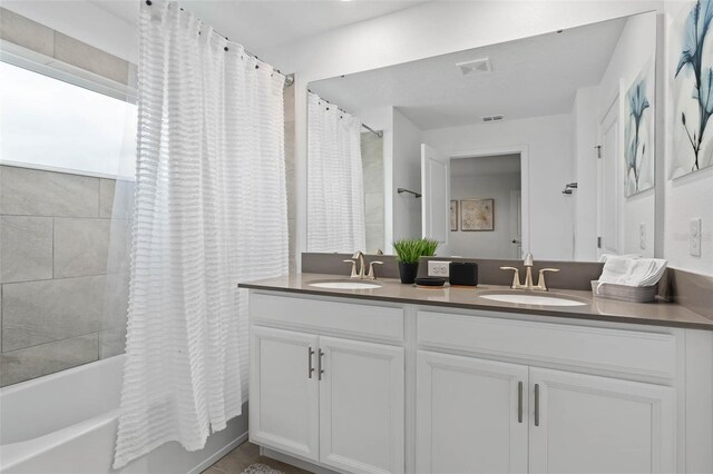 bathroom with double vanity, visible vents, shower / bathtub combination with curtain, and a sink