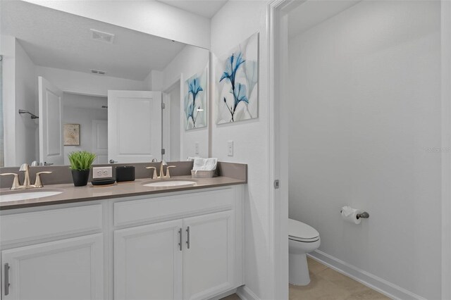 bathroom with double vanity, toilet, visible vents, and a sink