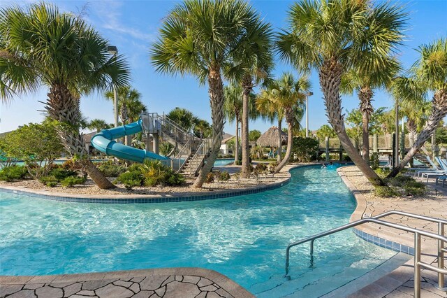 community pool with a water slide and a patio