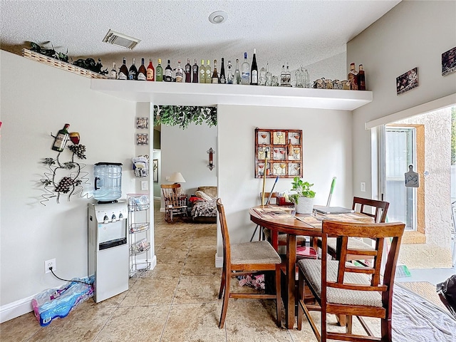 dining space with visible vents, a textured ceiling, and light tile patterned floors