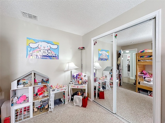 playroom featuring a textured ceiling, carpet flooring, and visible vents