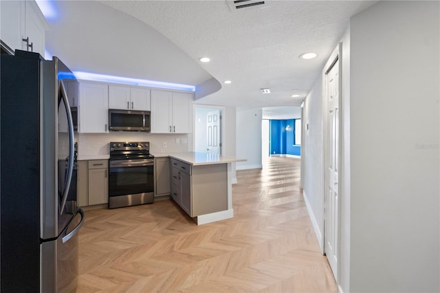 kitchen featuring visible vents, a peninsula, gray cabinets, stainless steel appliances, and a textured ceiling