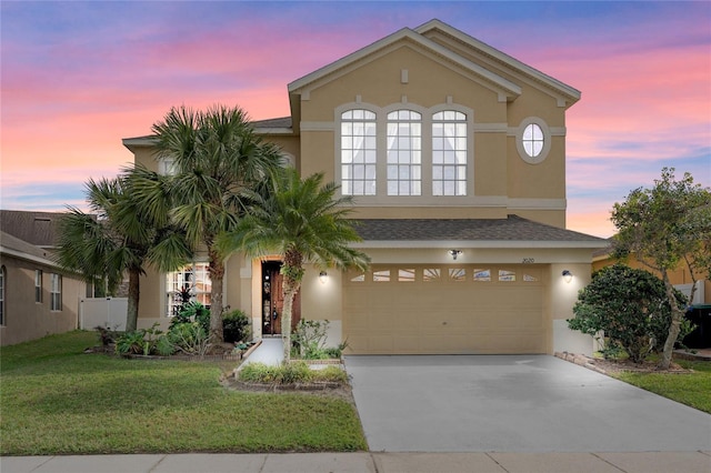 view of front of house featuring driveway, a yard, an attached garage, and stucco siding