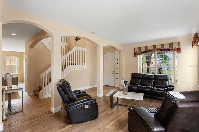 living room with light wood finished floors, stairs, and baseboards