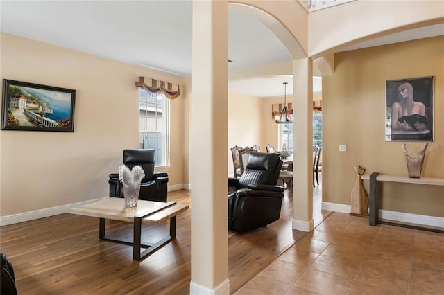 living area with arched walkways, plenty of natural light, wood finished floors, and baseboards