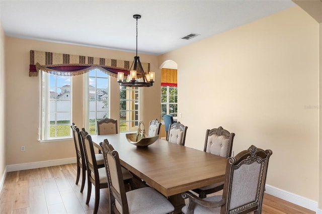 dining room featuring a chandelier, visible vents, light wood-style floors, and baseboards