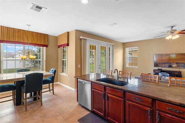 kitchen with reddish brown cabinets, visible vents, french doors, stainless steel dishwasher, and a sink