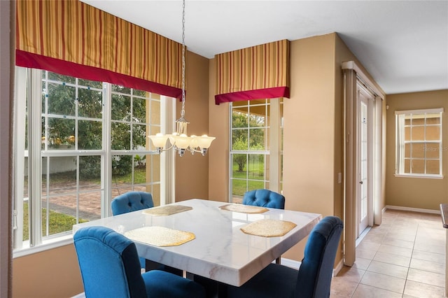 dining room featuring plenty of natural light, light tile patterned flooring, baseboards, and an inviting chandelier