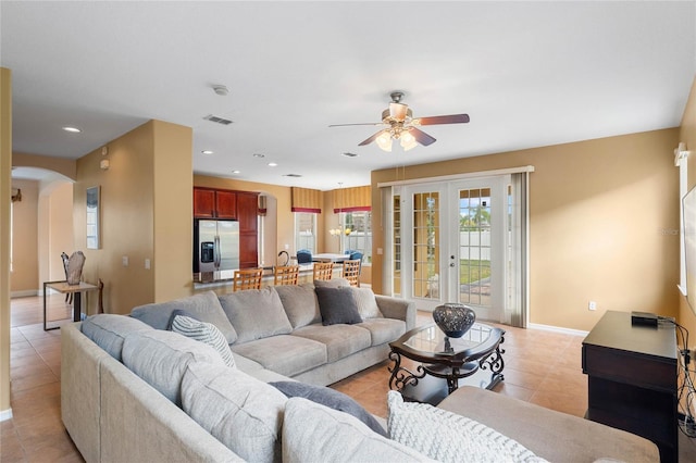 living room featuring arched walkways, french doors, light tile patterned floors, recessed lighting, and baseboards