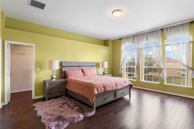 bedroom with wood finished floors, visible vents, and baseboards