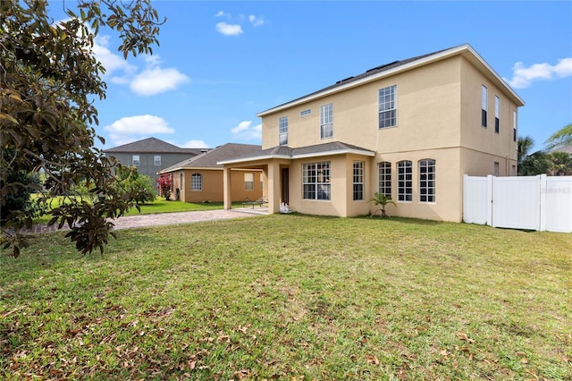 back of property featuring fence, a lawn, and stucco siding