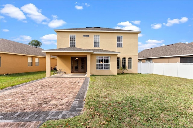 back of house with fence, french doors, a lawn, stucco siding, and a patio area