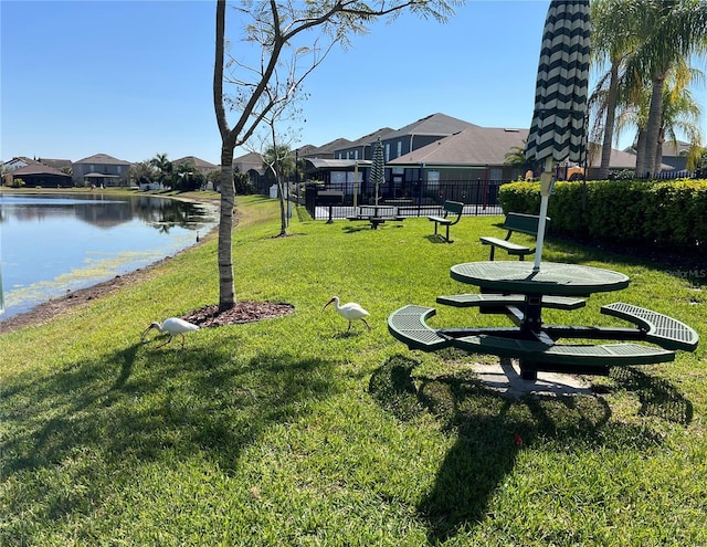 surrounding community featuring a yard, a water view, fence, and a residential view