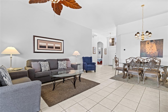 living room with light tile patterned floors, arched walkways, and ceiling fan with notable chandelier