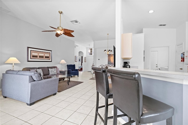 living room with arched walkways, light tile patterned floors, ceiling fan with notable chandelier, and visible vents