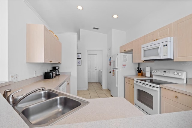 kitchen featuring white appliances, light tile patterned floors, light countertops, light brown cabinetry, and a sink