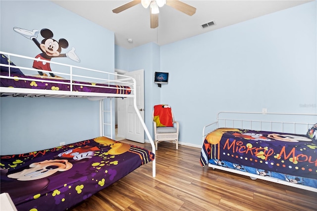 bedroom with a ceiling fan, wood finished floors, visible vents, and baseboards