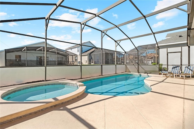 view of pool with a residential view, glass enclosure, a patio area, and a pool with connected hot tub