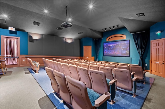 home theater room with a textured ceiling, carpet flooring, and visible vents