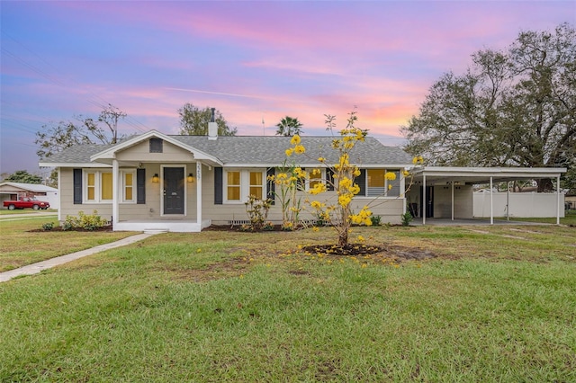 view of front of house with a shingled roof, a lawn, covered porch, fence, and a carport