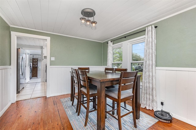 dining room with wood ceiling, a wainscoted wall, and hardwood / wood-style floors